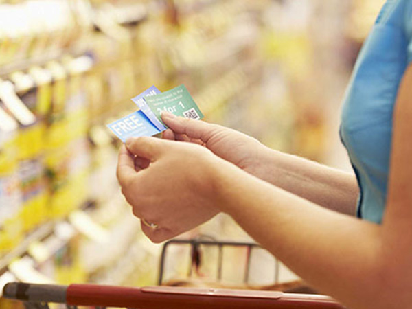 A photo of a shopper sorting through coupons in a grocery store aisle