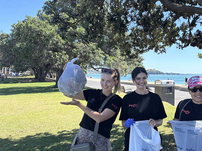 epay New Zealand team members collecting litter along Mission Bay beach during their Day of Caring community clean-up event