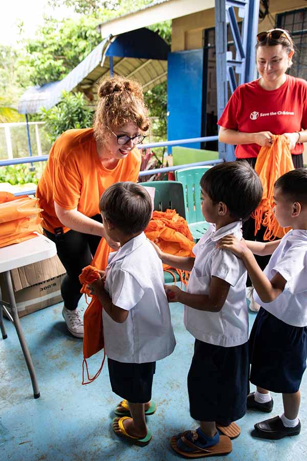 An image of Ria employees distributing supplies to children in the Philippines