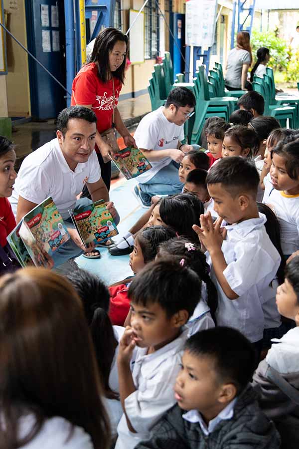 An image of Ria employees distributing supplies to children in the Philippines