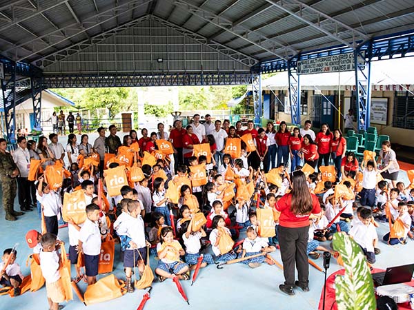 An image of Ria employees distributing supplies to children in the Philippines